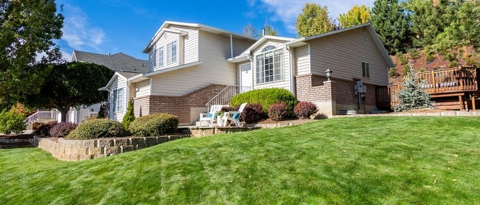 Well-maintained two-story brick and vinyl house with manicured lawn and landscaping