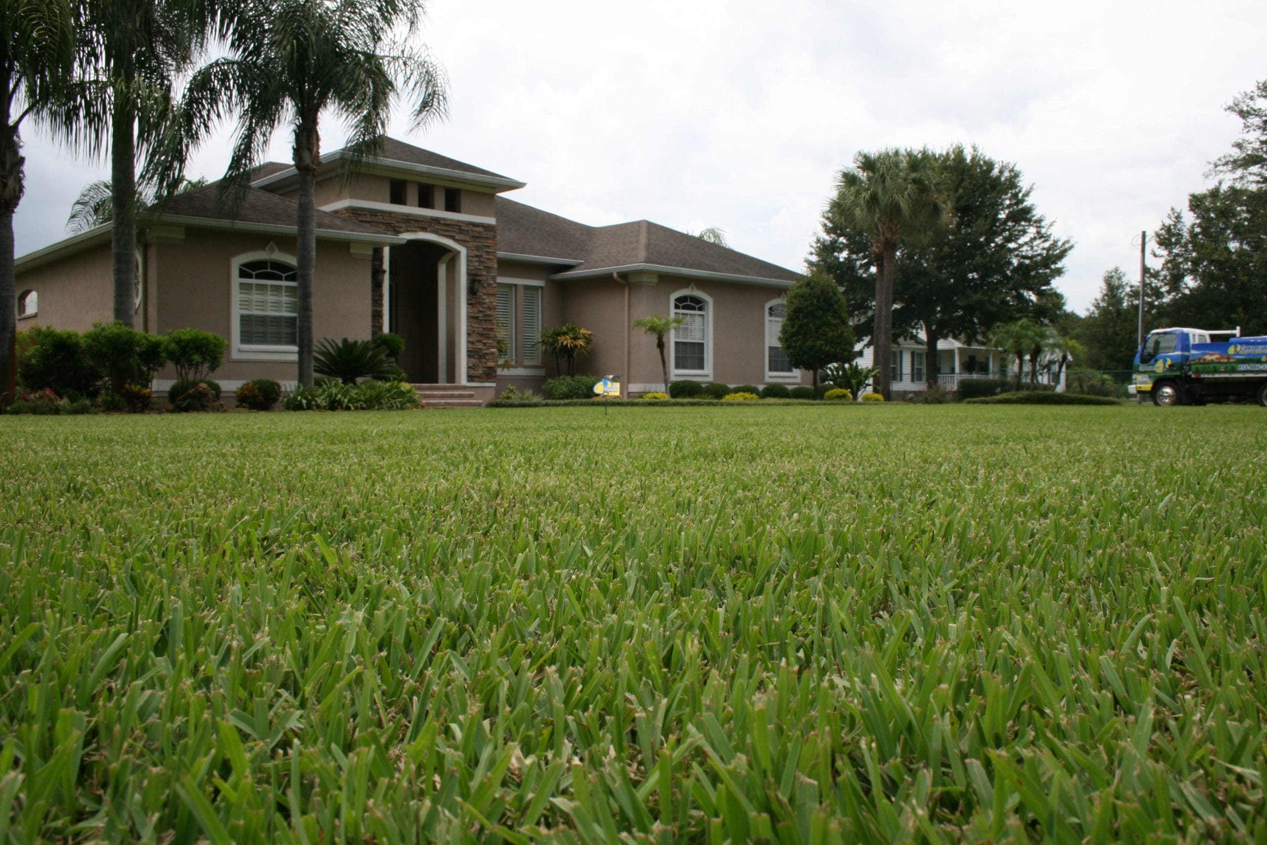 Technician applying Hydretain summer lawn care treatment to dry Seffner grass